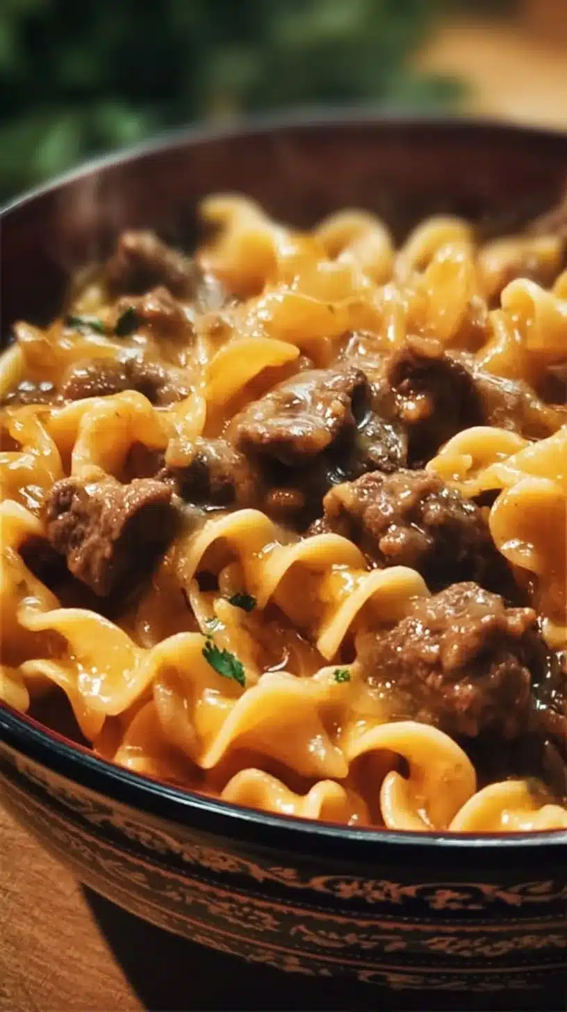 Crockpot cheesy beef and noodles served in a bowl with melted cheese